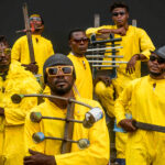 A group of musicians in yellow overalls in the film System-K